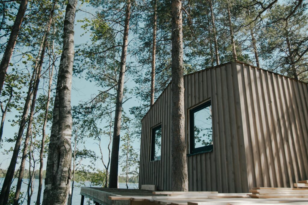 Beautiful low-angle shot of a wooden cabin in a serene forest setting by a lake.